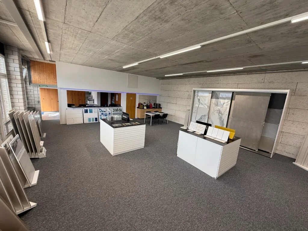 Spacious modern tile showroom with display counters, sample racks, and large stone slab panels on display.