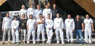 A team group photo of Ehrat AG employees in white uniforms gathered outside.