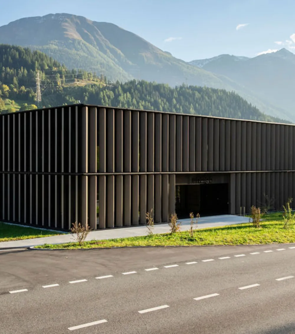 The sleek Endigo building facade is seen from street level with forested mountains behind it.