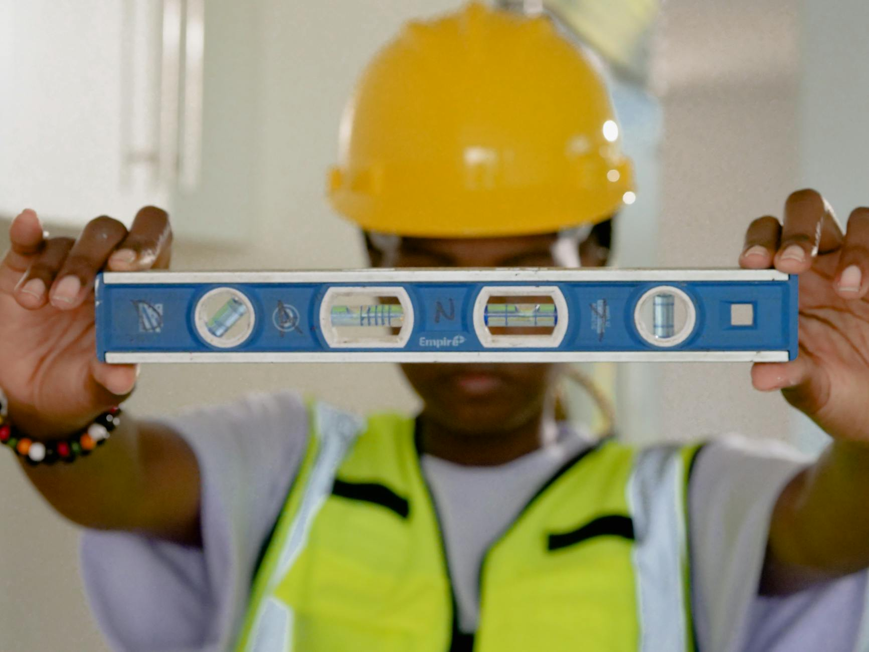 Renovierungsarbeiten an einem Schweizer Altbau: Ein Handwerker arbeitet an der historischen Holzfassade eines Chalets, während Baupläne und Werkzeuge im Vordergrund liegen.