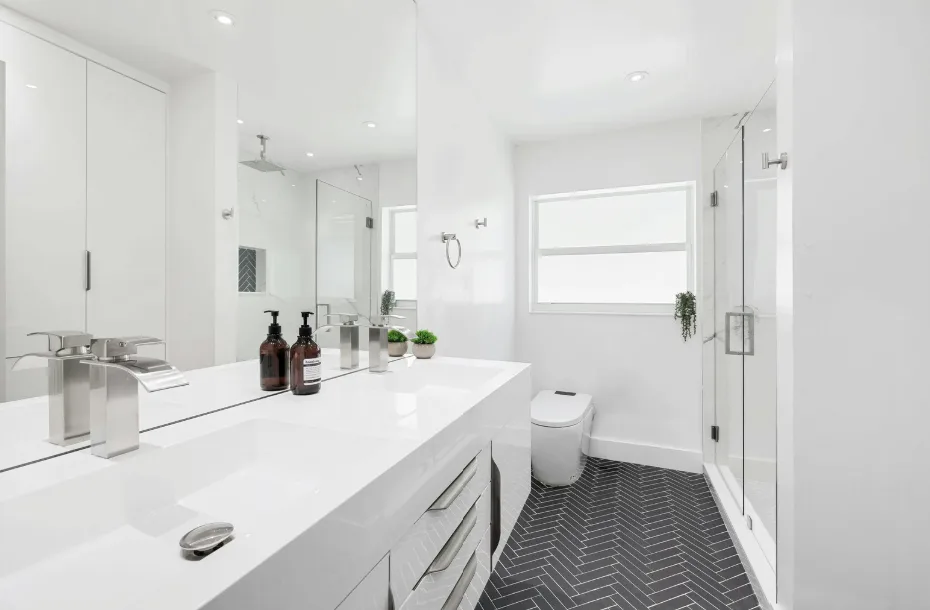 Ein modernes, helles Badezimmer in der Schweiz mit nachhaltigen Elementen wie wassersparenden Armaturen, rutschhemmendem Boden und dekorativen Pflanzen für eine behagliche Atmosphäre.