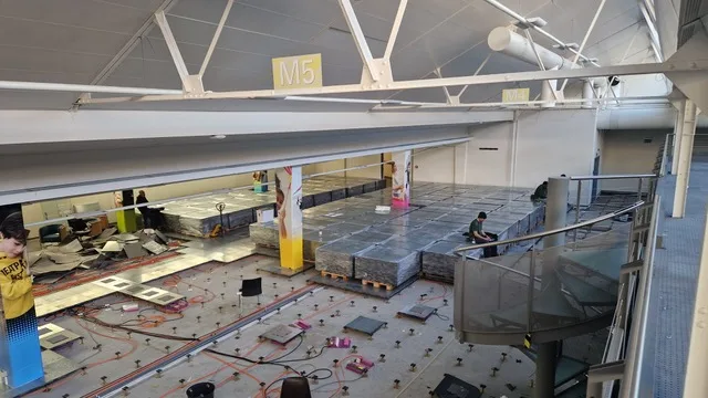 Elevated view of workers managing salvaged floor tiles and materials in a commercial building.
