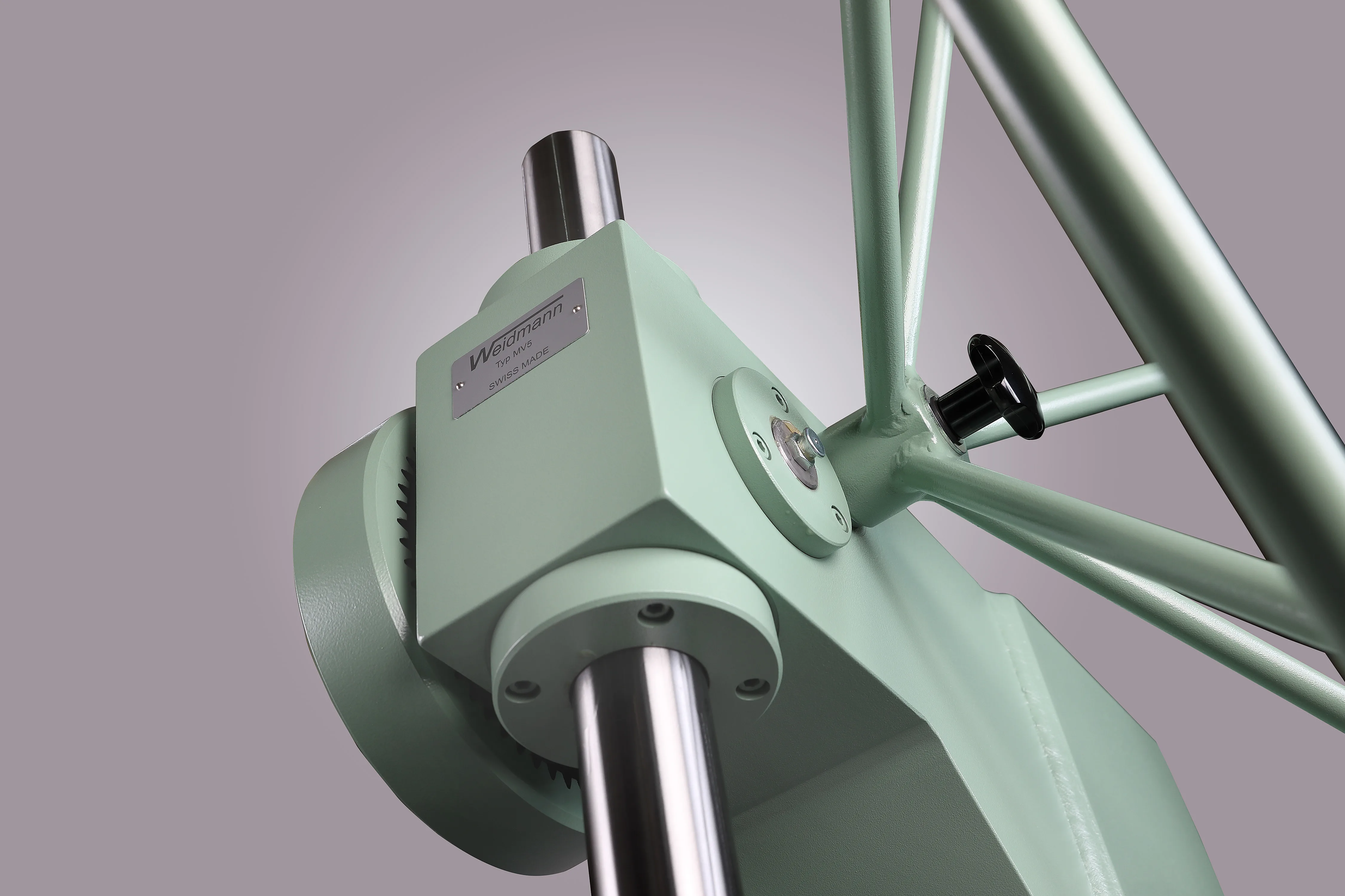 Close-up of a mint-green Weidmann Type MV5 Swiss-made mechanical press gearhead with polished steel shafts.