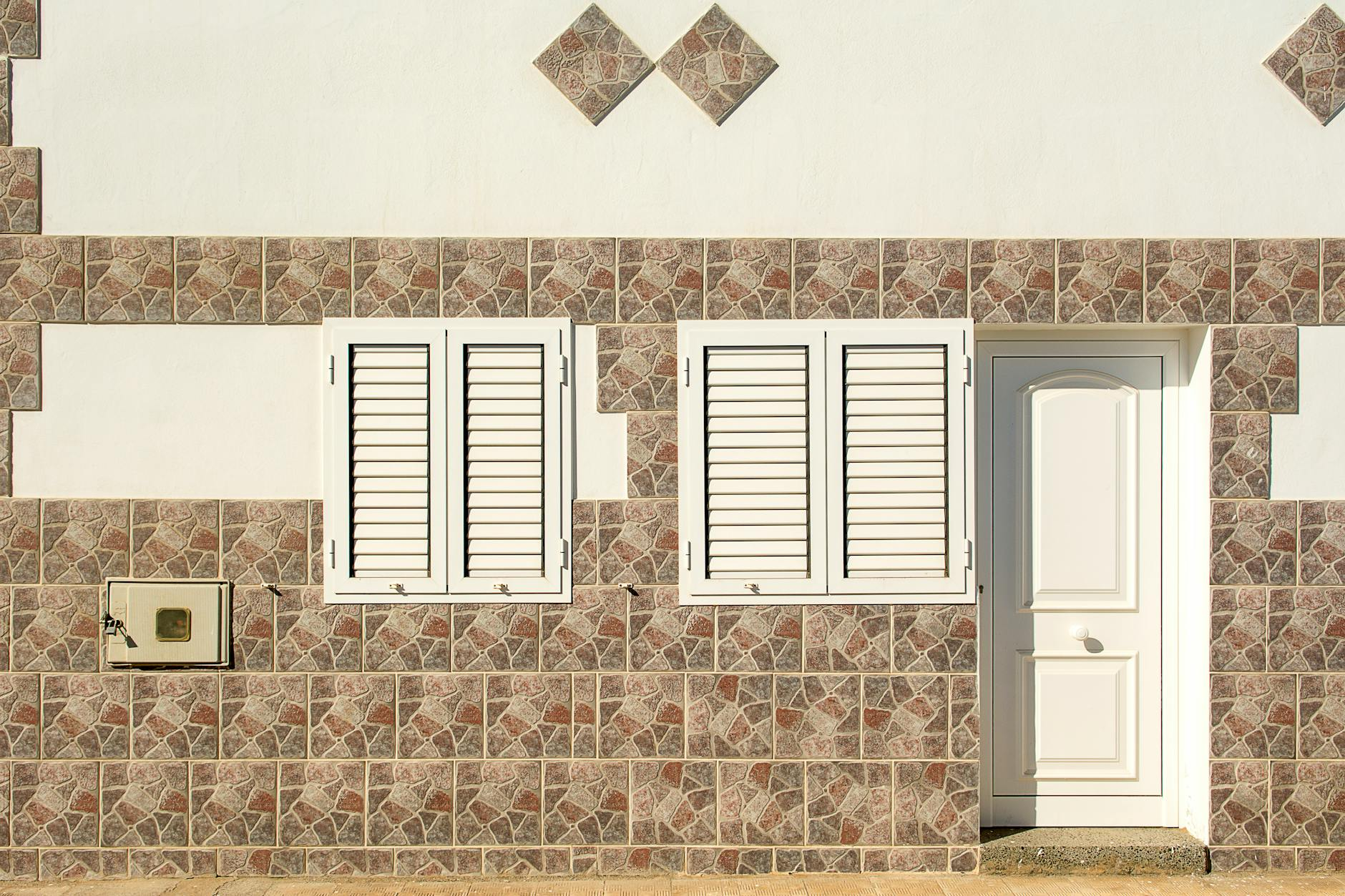 Ein Schweizer Einfamilienhaus während der energetischen Sanierung mit sichtbarer Fassadendämmung und neuen Fenstern, vor einer alpinen Landschaft.